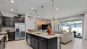 Una cocina moderna con una isla central, electrodomésticos de acero inoxidable e iluminación colgante.