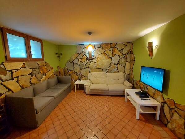 A living room with a stone wall, two sofas, a TV, and a small table.