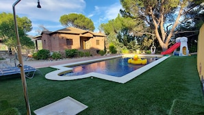 Quintal com piscina, pato inflável e escorrega.