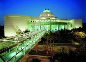 A modern building with a dome and a glass bridge leading to the entrance.