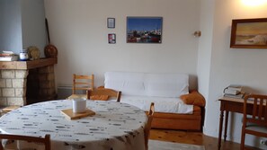 Un coin repas chaleureux avec une table ronde, des chaises, un canapé et une cheminée.