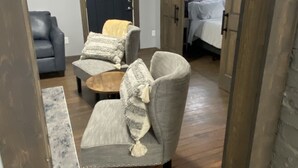 A room with a grey armchair, a blue door, and a bed with white bedding.