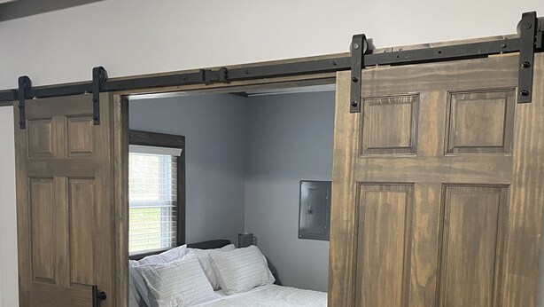 A bedroom with a bed, wooden sliding doors, and a window.