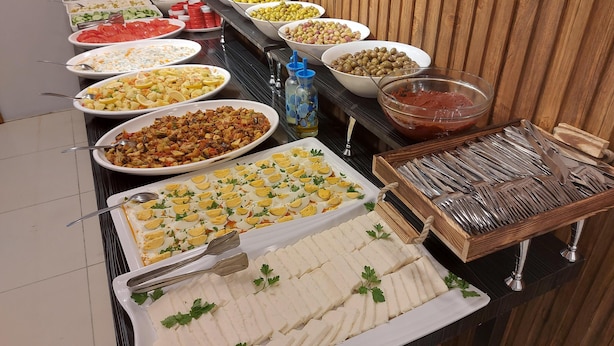 Buffet com diversas opções de comida, incluindo saladas, carnes e queijos.