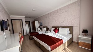 Quarto de hotel com duas camas, uma escrivaninha, televisão e guarda-roupa.