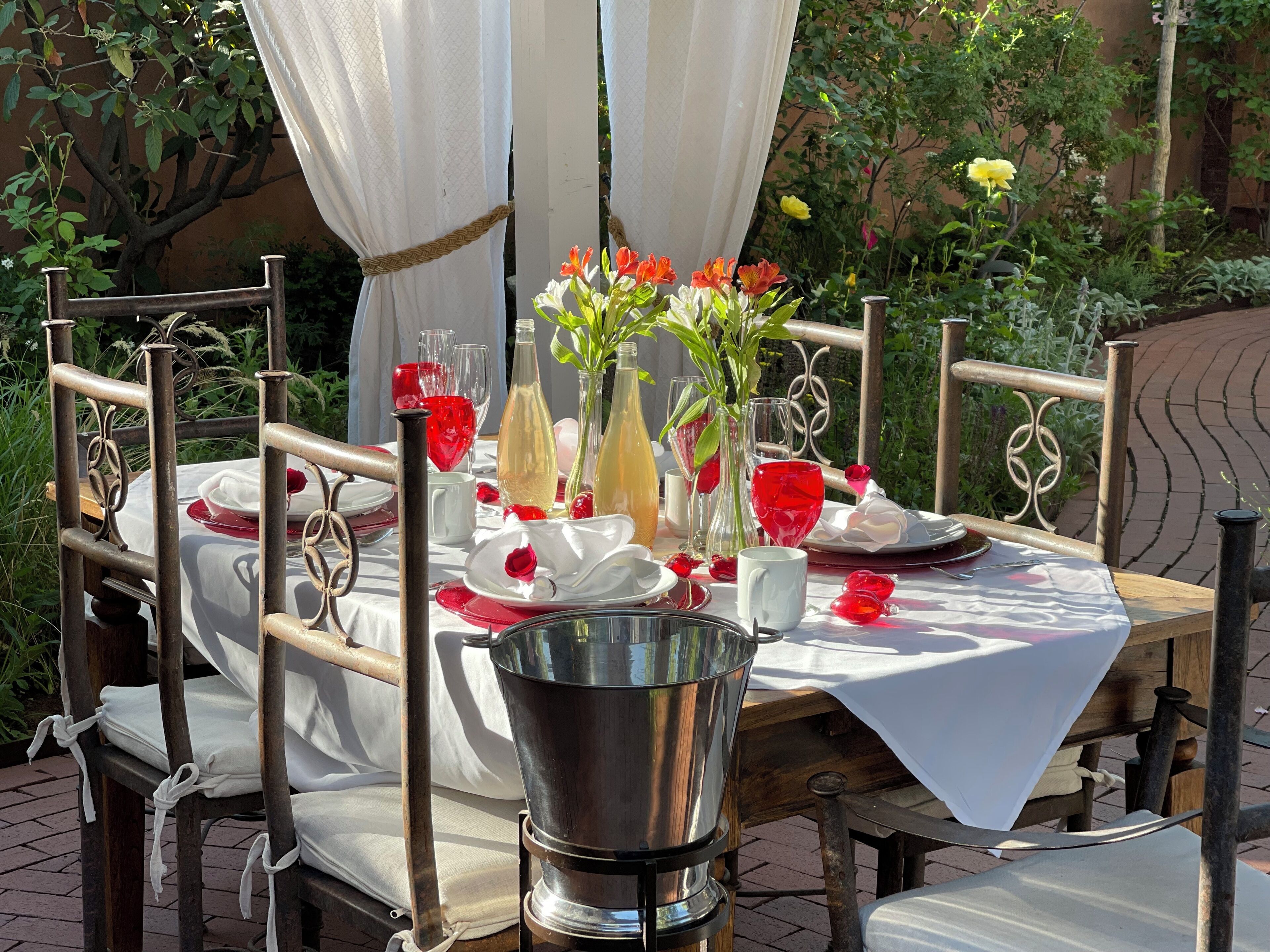 An outdoor dining area with a table set for four, surrounded by metal chairs.