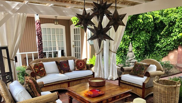 A cozy outdoor seating area with wicker furniture, a wooden coffee table, and a decorative metal star hanging from the ceiling.