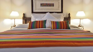 A neatly made bed with a colorful striped blanket, two pillows, and a framed artwork above it.