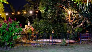 Un jardin avec une statue, un bassin et une clôture.