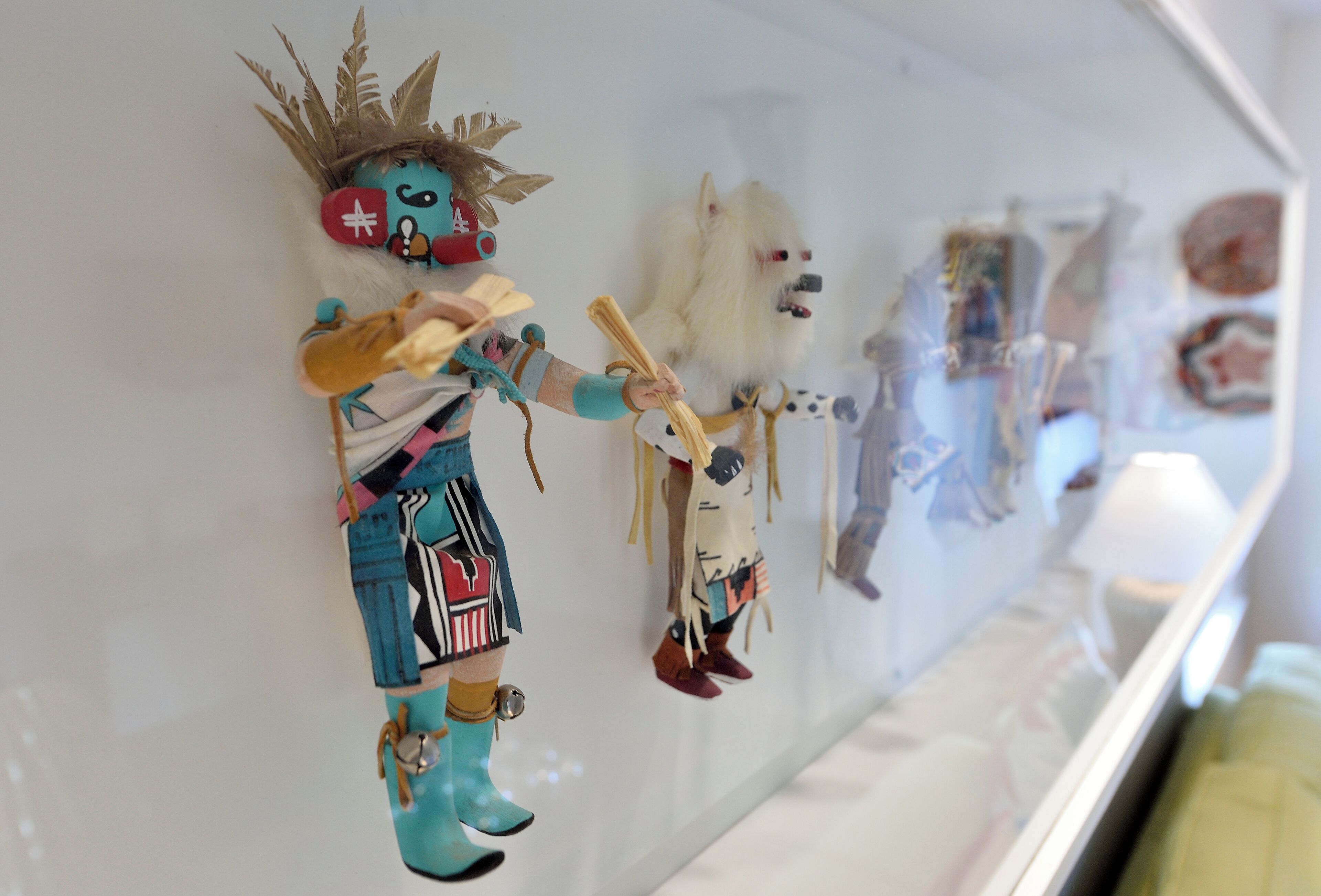 Eine Vitrine mit verschiedenen Dekorationselementen, darunter eine Figur mit Krone und eine hundähnliche Figur, die an einer Wand angebracht ist.