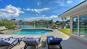 A swimming pool with lounge chairs, a clear sky, and a view of a marina.