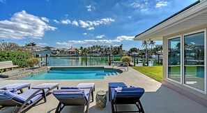 A swimming pool with lounge chairs, a clear sky, and a view of a marina.