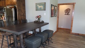 A modern kitchen with wooden cabinets, a stainless steel refrigerator, a dining table with four chairs, and a vase with flowers on the table. - 3/4 Mile from Wilderness Rider Buffalo Ranch,near Buffalo River w/RV Elec Hookup (Kingston)