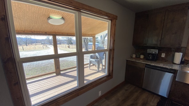 A kitchen with a large window, wooden flooring, and a view of a fenced outdoor area. - 3/4 Mile from Wilderness Rider Buffalo Ranch,near Buffalo River w/RV Elec Hookup (Kingston)