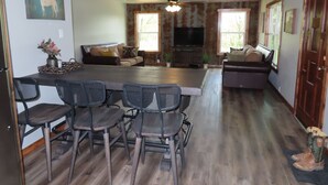 A spacious living area with a large island, dark wooden chairs, a sofa, and a television. - 3/4 Mile from Wilderness Rider Buffalo Ranch,near Buffalo River w/RV Elec Hookup (Kingston)