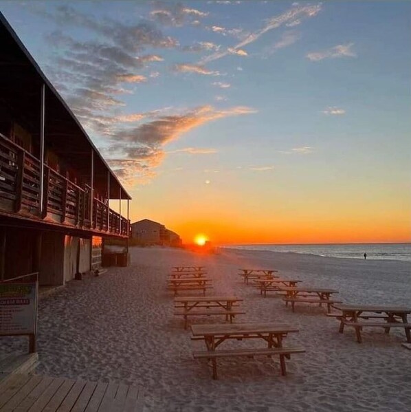 Enjoy outdoor dining or relaxation at this beachside spot with picnic tables and a nearby building with a balcony.