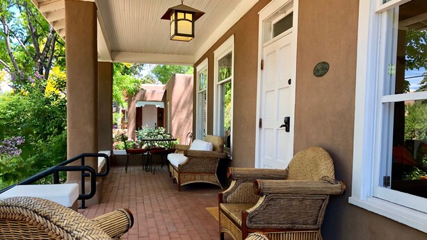 A covered patio area with wicker furniture, a table, and chairs.