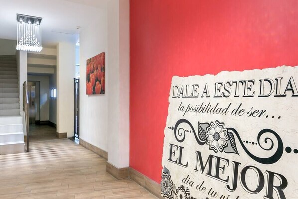 A hallway with a red accent wall and a motivational quote.