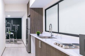 A modern kitchen with a stainless steel refrigerator, a sink with a modern faucet, and a small potted plant on the counter.