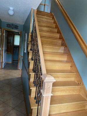 Staircase leads to an upper floor, flanked by light blue walls and a decorative welcome sign.