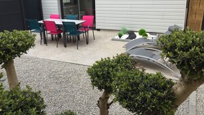 Un pati amb taula i cadires, envoltat de grava i petites plantes.