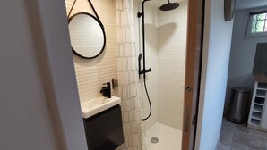 Pieni, moderni kylpyhuone, jossa on suihku, wc ja pesuallas.