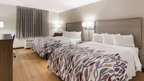 A hotel room with two beds, a desk, a chair, a lamp, and a window with curtains. - Red Roof Inn Chester (Chester)
