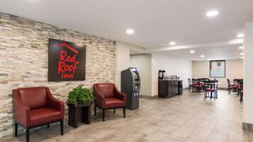 A Red Roof Inn lobby with seating, a self-service kiosk, and a projection screen in the background.