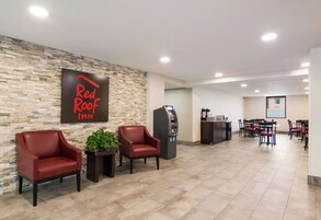 Vestíbulo de Red Roof Inn con asientos, un quiosco de autoservicio y una pantalla de proyección al fondo.