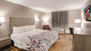 Une chambre d’hôtel avec un lit, un bureau, une chaise et un téléviseur.