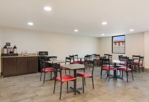 A conference room with tables and chairs, a kitchenette, and a projection screen on the wall. - Red Roof Inn Chester (Chester)