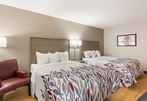 A hotel room with two beds, a red chair, and a framed picture on the wall. - Red Roof Inn Chester (Chester)