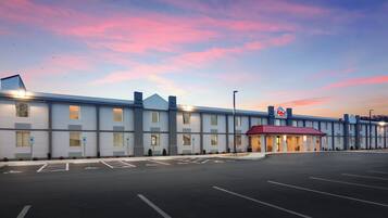A hotel with a parking lot and a building with a red roof.