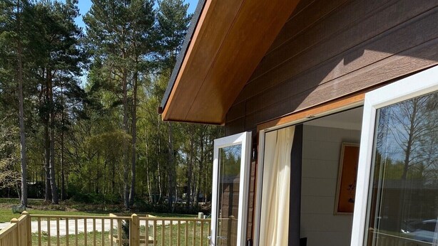 A wooden deck with a sliding glass door leading to a room. - Hollicarrs - Newlands (York)