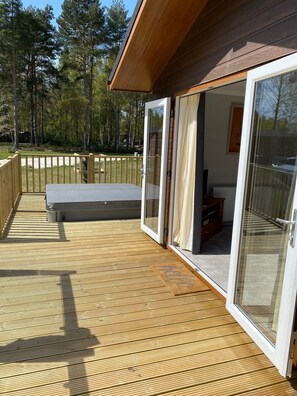 A wooden deck with a sliding glass door leading to a room with a television. - Hollicarrs - Newlands (York)