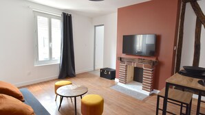 Una sala de estar moderna con chimenea, un televisor montado en la pared y un comedor con mesa y sillas.