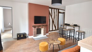 Una sala de estar moderna con chimenea, televisor montado en la pared y comedor con taburetes de bar.