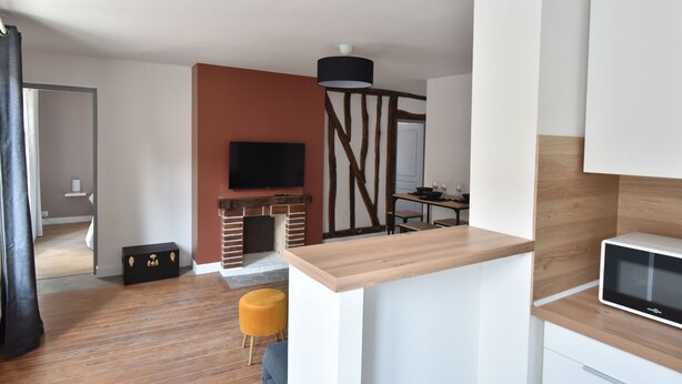 Una cocina moderna con encimera de madera, microondas integrado y televisión sobre la chimenea.