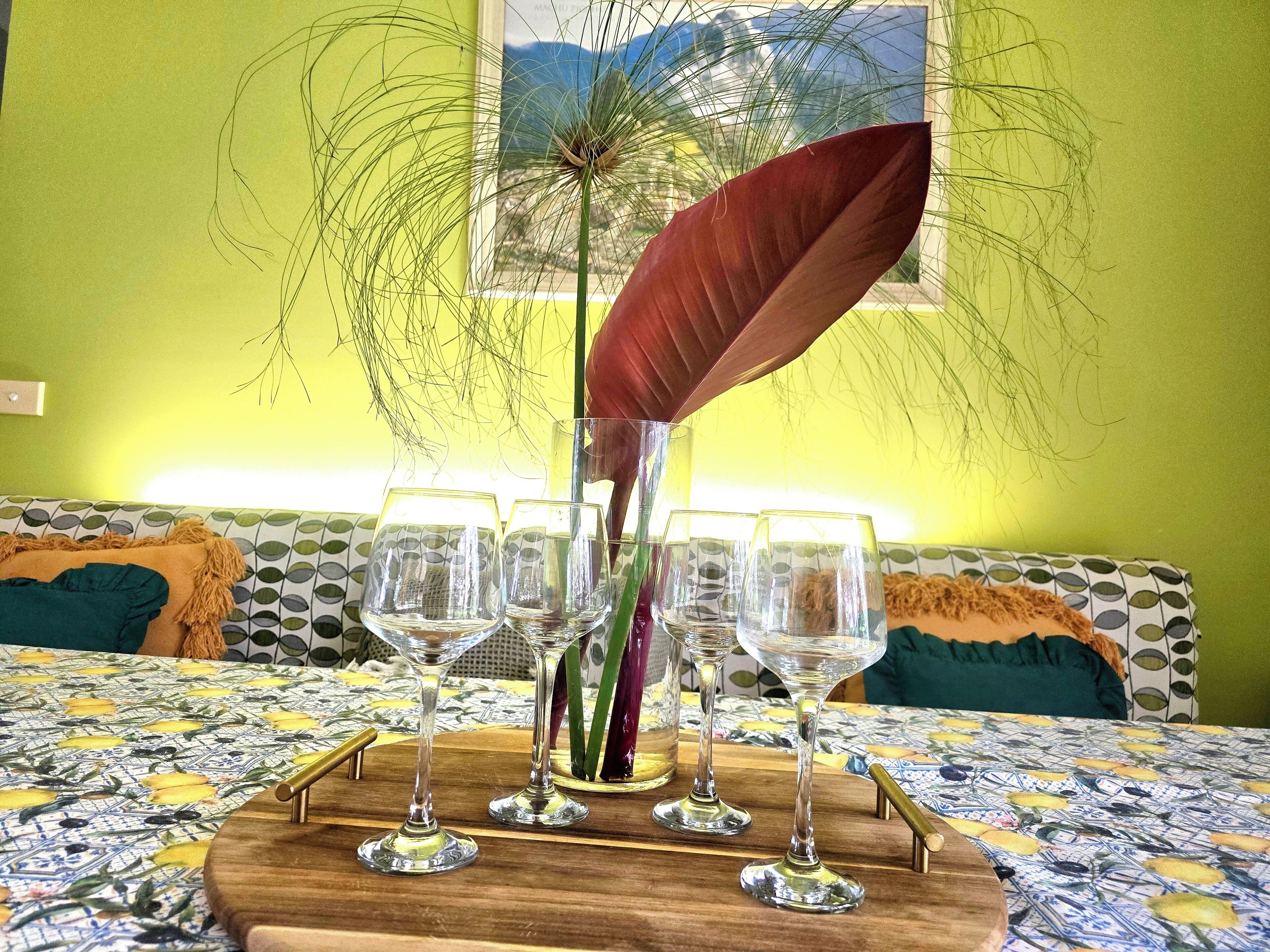 Une table avec quatre verres à vin, une plante décorative et un plateau en bois.
