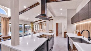 A modern kitchen with a central island, built-in appliances, and a view of a pool. - Wind Hill in Pioneertown & Joshua Tree (Yucca Valley)