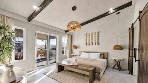 A modern bedroom with a large bed, a coffee table, a bedside table, and a view of the outdoors. - Wind Hill in Pioneertown & Joshua Tree (Yucca Valley)