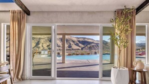A room with a sliding glass door leading to a pool area with a mountain view. - Wind Hill in Pioneertown & Joshua Tree (Yucca Valley)