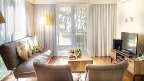 Un salon moderne comprenant un canapé, deux fauteuils, une table basse, un téléviseur et une bibliothèque.