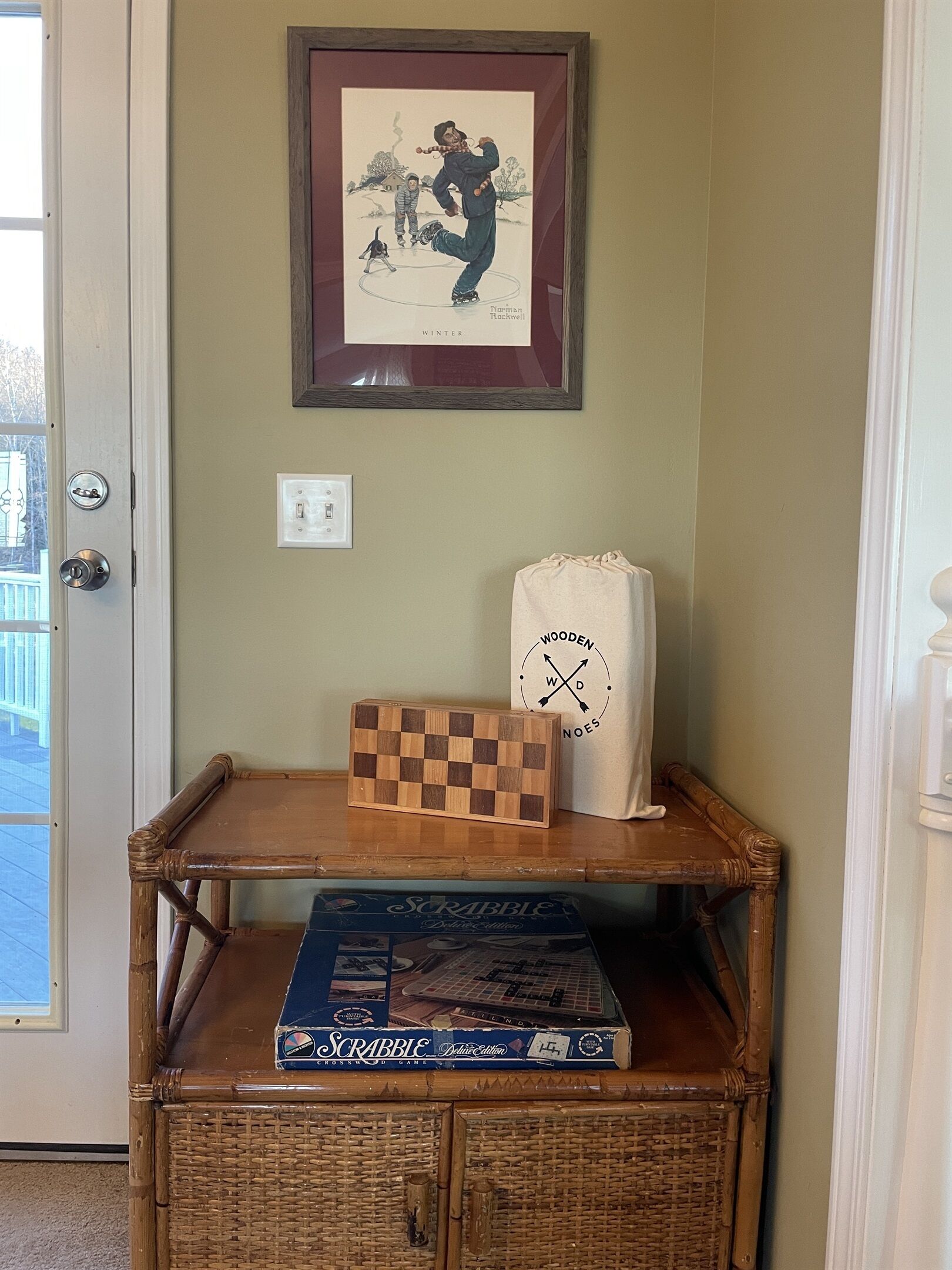 A wooden bench with a Scrabble box and a framed picture on it.