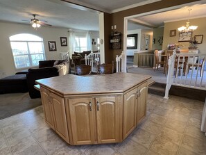 A spacious living area with a large wooden island, a dining area with a white railing, and a view of the city through a large window. - Buck's Run Breathtaking long distance valley views (Cooperstown)