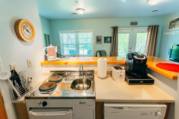 A compact kitchen with a sink, stove, and coffee maker.