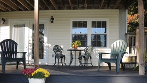 Eine Veranda mit vier Stühlen, einem Tisch und einem Blumentopf mit gelben Blüten.