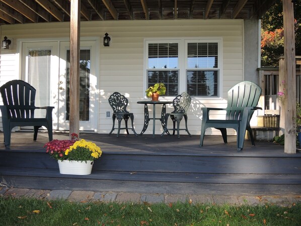 A porch with four chairs, a table, and a potted plant with yellow flowers.