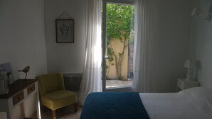 A bedroom with a bed, a chair, a desk, and a window with curtains. - Charming rentals (Mazan)