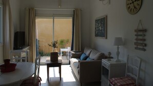 A living room with a sofa, a table, a TV, and a window with curtains. - Charming rentals (Mazan)